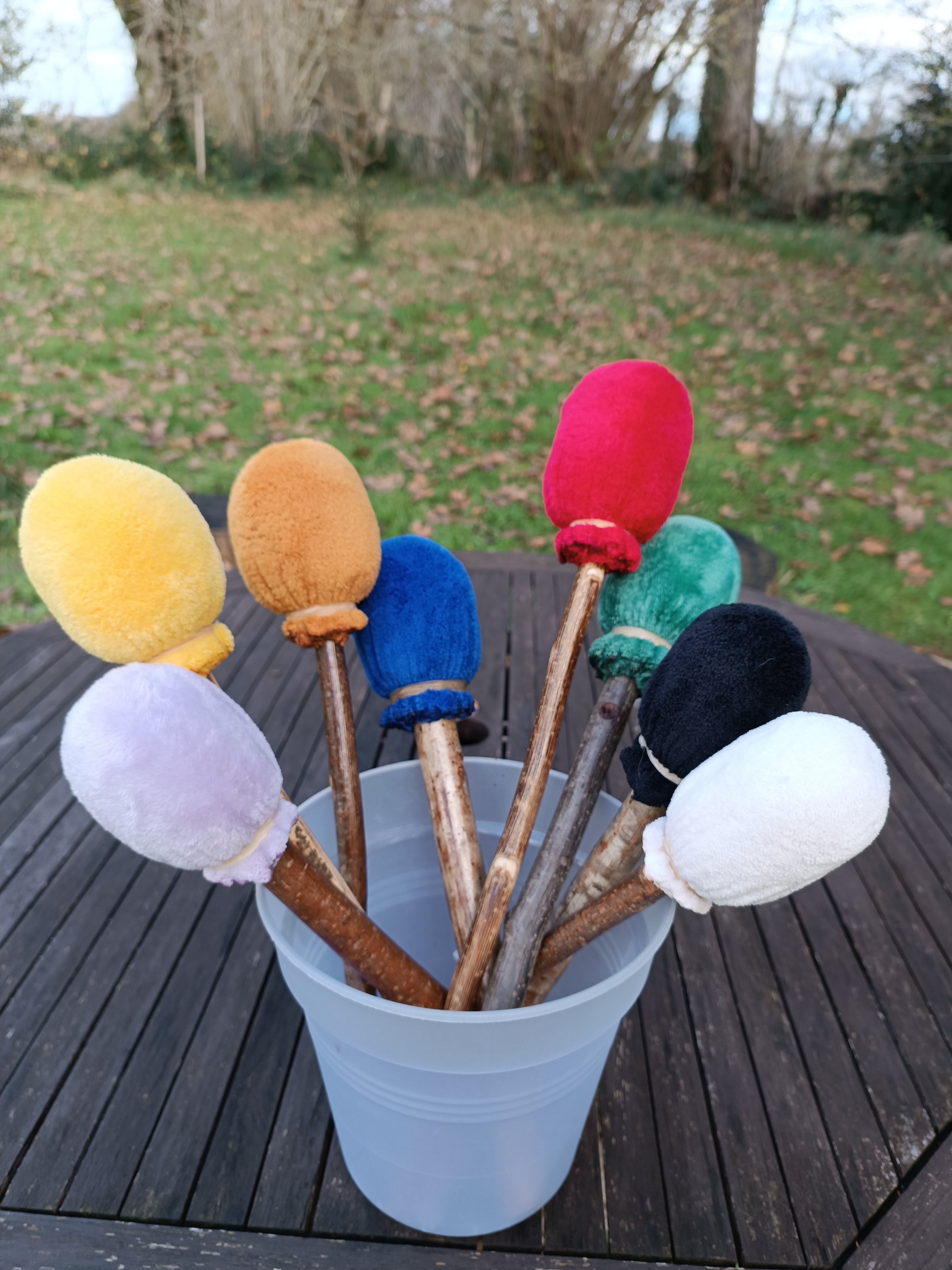 Plusieurs mailloches de couleurs posées dans un seau